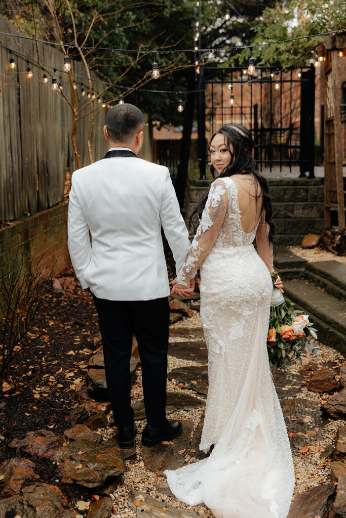 Destination elopement photographer captures bride and groom holding hands while bride looks over shoulder