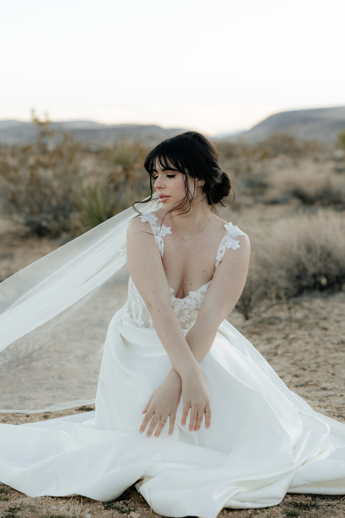 Destination elopement photographer captures bride sitting in desert after Las Vegas elopement