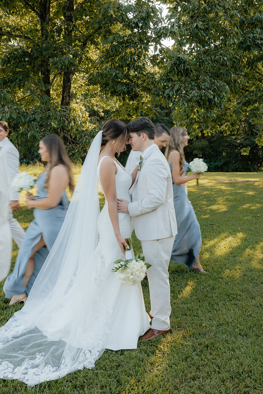 Tennessee wedding photographer captures couple kissing while bridal party walks around them