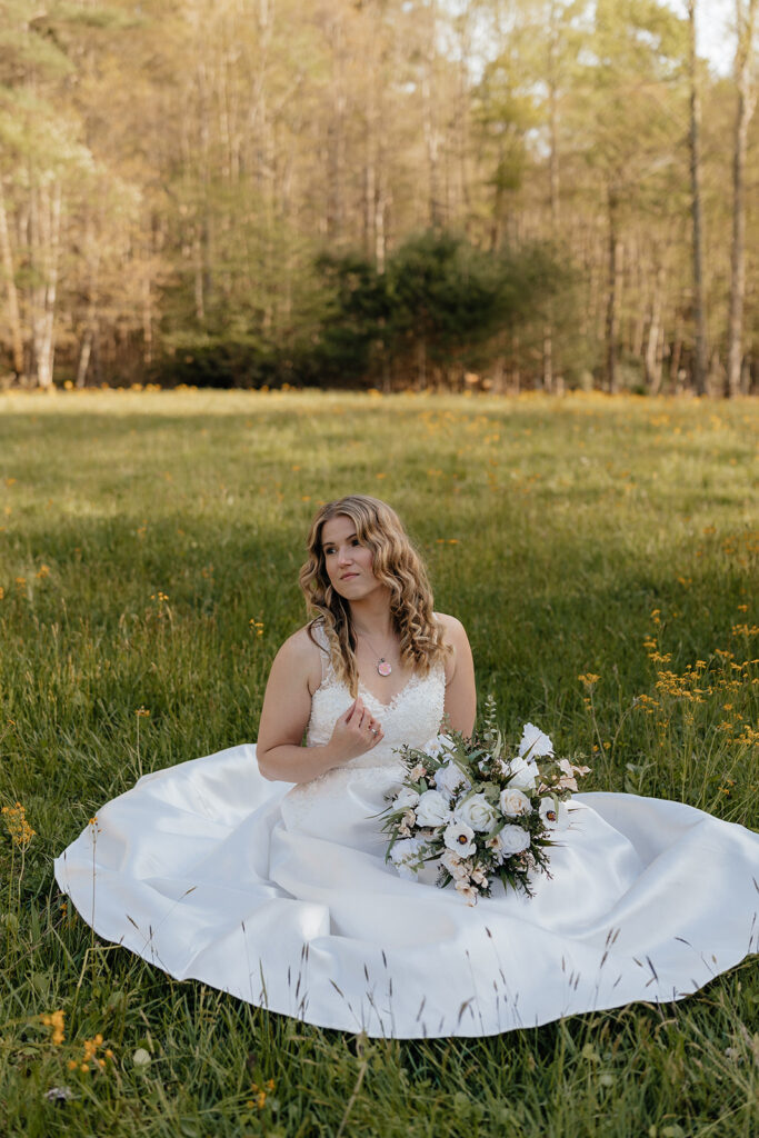 Destination elopement photographer captures bride sitting in grass holding bouquet