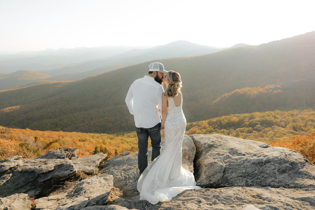 Destination wedding photographer captures bride and groom kissing while overlooking mountains