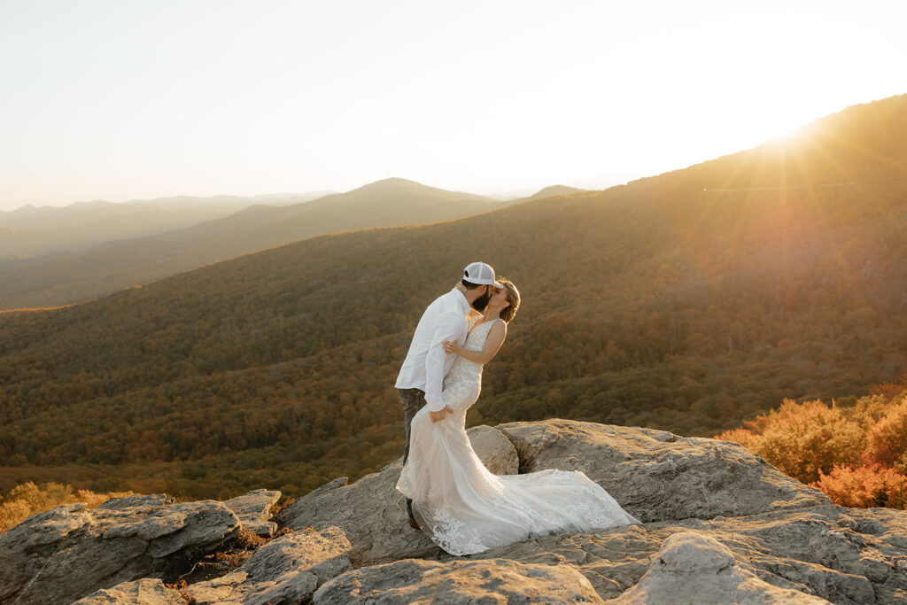 Destination wedding photographer captures bride and groom kissing on boulder after wedding ceremony