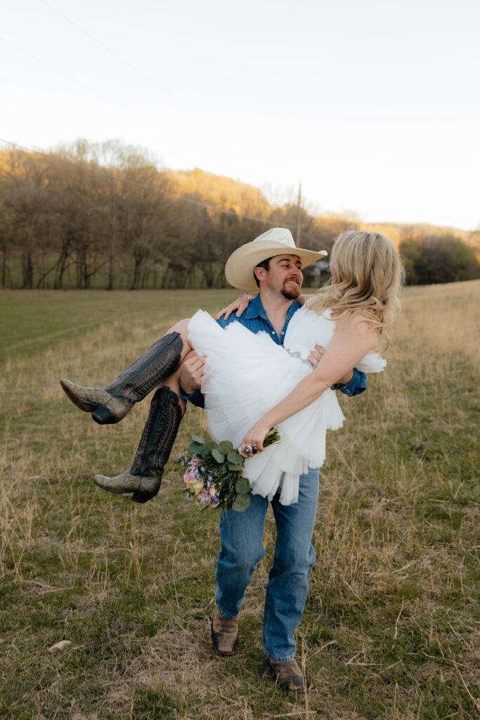 Couples photoshoot, man carrying girlfriend through field with flowers