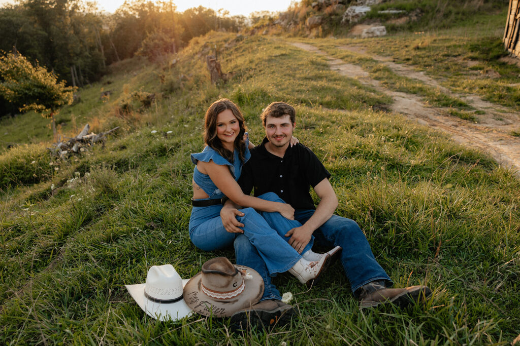 Tennessee elopement photographer captures man and woman sitting together on grass with cowboy hats in front of them during mountain engagement photos